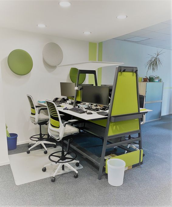 Raum mit Tisch und 4 Arbeitsplätzen in grün, weiß, anthrazit gehalten. Open Space Arbeitsplätze.